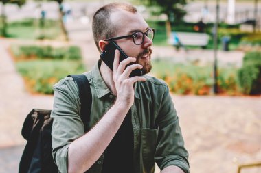 Neşeli hipster blogger new city seyahat ve akıllı telefon görüşmesi için gezici bağlantıyla sırt çantası ile. Kentsel ortamda hücresel ayakta konuşurken turist genç adam