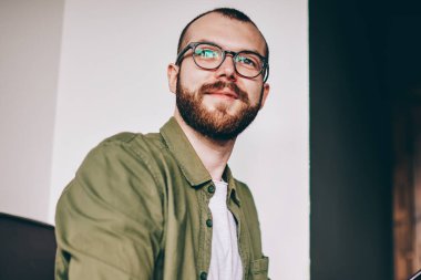 Durulması gülümseyen ve uzak profil sayfası laptop ile masada oturan smartphone güncelleştirilirken arıyorum genç adam sakallı. Düşünceli hipster adam netbook, uzaktan çalışma sırasında teephone üzerinde SMS gönderme