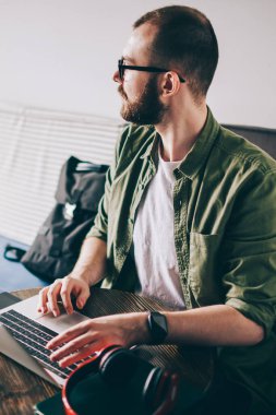 Düşünceli genç modern bilgisayarda kablosuz internet kafede oturan kullanarak yükleme uygulama adam. Uzak mesafe işi sırasında yazılım netbook üzerinde güncelleştirilirken seyir durulması hipster adam