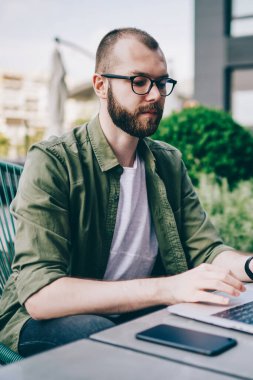 Dalgın sakallı serbest meslek yüksek hızlı 4 g kullanarak dizüstü cihaz üzerinde internet sitelerinde bilgi arama Internet. Genç adam rahat kıyafet, uzaktan çalışma bilgisayardaki bilgilere klavye