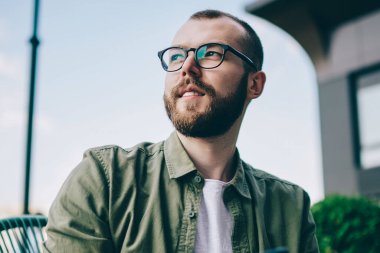 Durulması Smartphone cep telefonu ile blog yayında için fikri üzerine düşünürken uzakta görünen genç adam sakallı. Düşünceli hipster adam profil sayfası telefon aygıtı yüksek hızlı Internet bağlantısı kullanarak güncelleştirme