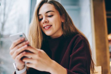 Akıllı telefon elinde tutan ve 4 g cep telefonu aracılığıyla kapalı kablosuz bağlı metin mesajı yazmaya mutlu hippi kız üniversite rahat kafeteryada, istirahat sırasında sohbet Kafkas pozitif kadın