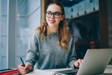 Modern netbook üzerinde arama bilgi kapalı kız öğrencinin harcama zaman üniversite kütüphanesi, mutlu kadın dizüstü bilgisayar kullanan öğrenme dil için bu geliştirici rahat olumlu giyinmiş