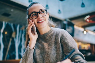 Mutlu kadın yazar uzağa oturma sırasında kahve dükkanı bekleyen arkadaş oluşturma yeni makale, 4 g cep telefonu üzerinden başarılı gülümseyen hippi kız gözlük tebliğ bakarak ve Internet