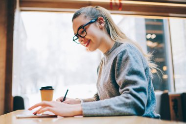 Mutlu kadın blogger yazarak yeni metin mesajları ve oluşturma yeni yazı kahve dükkanında oturmuş ve proje bilgilerini arama olumlu kadın sosyal ağlar için için smartphone uygulama kullanarak