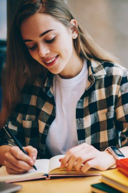 Sosyal ağlar, yeni takipçileri çekmek için kendi içerik Web sitesi pencere yakınındaki Üniversitesi Kütüphanesi'nde otururken mutlu kadın planlama gezi için yeni makale yazıyorsun, pozitif kadın blogger