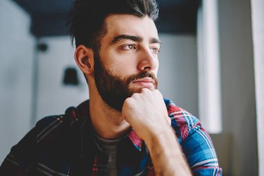 Dalgın hipster adam giymek rahat giyim düşünceli uzak kapalı otururken bakarak, rüya beyaz adam öğrenci yarın sınav ve bekleyen arkadaş üniversite kampüsü hakkında düşünme sakallı