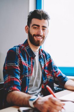 Yeni uygulama, şirket için yeni logo içinde ders kitabı yazma mutlu başarılı grafik tasarımcı yüklenirken yeni Web sitesi oluşturma netbook ile çalışan neşeli erkek yazılım geliştirici portresi