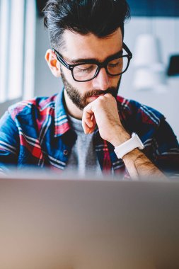 Düşünceli erkek metin yazarı alan, konsantre adam için kablosuz bağlıyken netbook kullanarak yeni Web sayfası oluşturma hakkında düşünme coworking, modern dizüstü bilgisayar ile vakit gözlük
