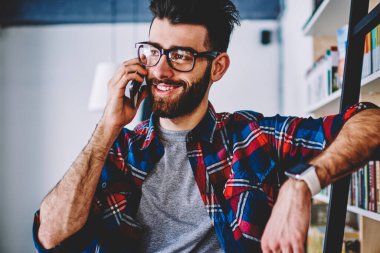 Mutlu başarılı hipster adam adam üniversite kitaplığında modern smartphone kullanarak pozitif muhabbet gülümseyen en iyi arkadaşı yolu ile cep telefonu wuth 4 g bağlantı kitap deposunda bahsediyoruz