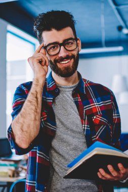 Üniversite Kampüsü ve kameraya arıyor ilginç kitap Eyewear genç adam gülümsüyor, trendy mutlu başarılı erkek öğrenci giyim otodidakt edebiyat zevk üzerinde harcama serbest zaman