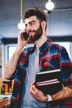 Başarılı adam olumlu hücresel yeni uygulama ile Üniversitesi kampüsünde muhabbet gülümseyen, mutlu hipster adam giymek Kitabevi, serbest zaman zevk ve teknolojisini kullanarak rahat konum