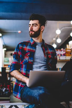 Hipster adam bir kenara tatilinde dizüstü bilgisayar öğrenme e seyir düşünceli durulması, merdiven Üniversitesi Kütüphanesi'nde oturan ve wifi için bağlı netbook üzerinde çalışan erkek öğrenci konsantre