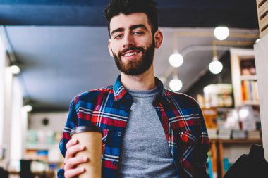 Sabah paket servisi olan restoran kahve Üniversitesi Kampüsü zevk ve e öğrenme, dizüstü bilgisayarda tatilinde iş kamera bakarak mutlu erkek metin yazarı için vakit başarılı hipster adam portresi