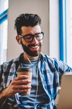 Modern dizüstü bilgisayardaki sabah paket servisi olan restoran kahve kapalı, tadını çıkarırken mutlu pozitif erkek blogger kulaklık ile müzik dinleme göster komedi izlemek ve arkadaşlarınızla sohbet neşeli hipster adam