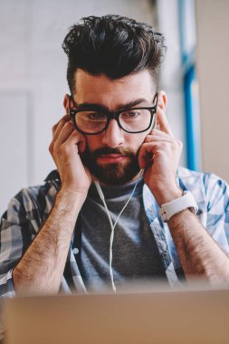 Genç yakışıklı erkek blogger izlerken Haritayı online dinlemek için kulaklık kullanarak dizüstü bilgisayarda, yüksek hacimli ve çalma listesi kapalı tadını çıkarırken netbook üzerinde kısa mesaj okuma adam yoğunlaşmıştır.