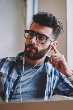 Düşünceli hipster adam bir kenara süre dinleme ilginç radyo sinyalleriyle iletilen kitap elektronik kulaklık üzerinden tatilinde e öğrenme laptop, dalgın Genç beyaz adam alan coworking adlı müzik keyfi arıyor
