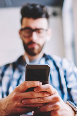 Cep telefonu ve paket servisi olan restoran kahve, sosyal ağlar, uzay coworking 4 g bağlantı ile modern smartphone kullanarak metin mesajı yazmaya genç hipster adam erkek ellerinde seçici odak