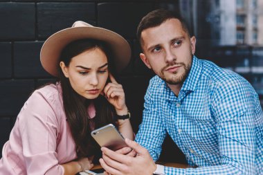 Modern café iç oturan erkek arkadaşının ellerini Smartphone cep telefonu ile gelen bildirim okuma dalgın kız arkadaşı. Genç adam gösteren telefon sms mesajı ile durulması toplantı sırasında güzel karısı
