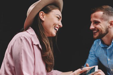 Neşeli büyüleyici kız arkadaşı ile birlikte sosyal ağlar komik bof kafede toplantı sırasında tartışırken erkek gülüyor. Mutlu çift aşık eğleniyor harcama zaman Cafe