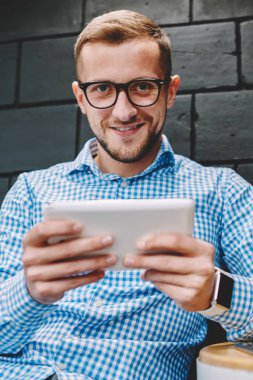 Yarım uzunluk portre pozitif gencin 4 g kullanarak modern dokunmatik yüzey profili güncelleştirilirken kameraya gülümseyen Eyewear Internet. Sohbet online tablet cihaz üzerinde neşeli hipster blogger