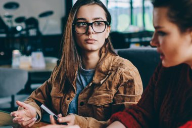Seçici odak birlikte teknolojisini kullanarak başlangıç proje üzerinde düşünme eğitimi iki konsantre kadınlar dikkatle kız arkadaşı, dinleme college Kampüsü oturan gözlük ciddi hipster kız üzerinde
