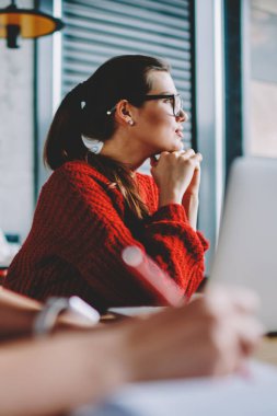 Bin yıllık kadın içinde gözlük düşünceli bir kenara uzay coworking ve webinar, dalgın genç kadın freelancer makale için Web sitesi oluşturmak için zaman geçirmek için bekleyen oturma seyir durulması