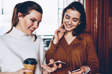 Neşeli kadın blogcular akıllı telefonlar, zaman takipçileri üzerinden cep telefonları kahve dükkanında dinlenme ile birlikte sohbet tadını kadın gülümseyerek olumlu bluetooth bağlantısı ile bilgi paylaşımı