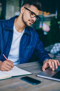 Dizüstü bilgisayar üzerinden online ders öğrenme ve notlar, öğretici izlemek için netbook kullanarak ağları üzerinden bilgi belirterek dalgın hipster adam kazanıyor Gözlük Genç beyaz erkek öğrenci