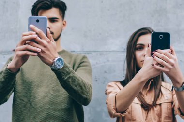 Cep telefonları online sohbet üzerinde konsantre yüzlerini önünde gerçek hayat iletişim görmezden tutan gençler, modern akıllı telefonlar ayakta duvara bağımlısı erkek ve kadın arkadaş