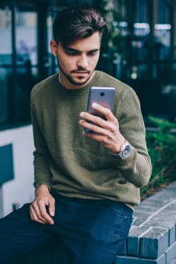 Dalgın Kafkas erkek 4 g kullanarak ağ bağlantılarını en son haberleri okumak için cep telefonunuzun internet, konsantre yeni veri kaynakları kontrol ve açık havada vakit smartphone üzerinden posta gönderme blogger