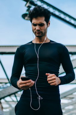 Cep telefonu 4 g bağlantı sırasında egzersiz açık havada, aktif erkek koşucu telefon yayınlamaya başlamak önce çalma listesi şarkıları motivasyon kontrol kullanarak mesaj okuma eşofman ciddi adam