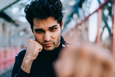 Championat için hazırlamak için yarım uzunluk portre konsantre adam boksör gücü yapıyor yumruklar ve kardiyo eğitim açık havada sırasında kameraya baktığımızda, Erkek bulanık cephe süsleme yumruk sıkılı