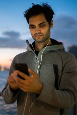 Modern cep telefonu ve açık havada, kardiyo eğitim için motivasyon çalma listesi güncelleme uygulaması aracılığıyla elektronik kulaklık spor haberleri hakkında ses dinleme güçlü erkek koşucu chat yapan sporcu