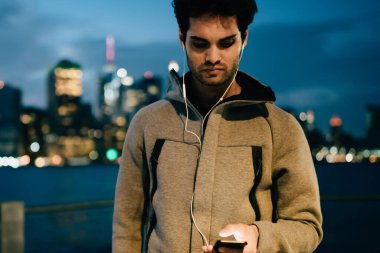 Eğitim içerik spor blog üstünde smartphone becerikli alet egzersiz, genç atlet yazarak metin mesajı birlikte koşu için arkadaşına dinleme ses kitapta ise akşam hakkında makale okuma Erkek atlet