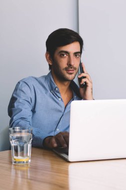 4 g için bağlı iş ve teknoloji, cam su ve dizüstü bilgisayar aygıtla kendi masasında oturan ve telefon görüşmesi yapma yakışıklı Hintli şirket yöneticisi portresi kavramı Internet