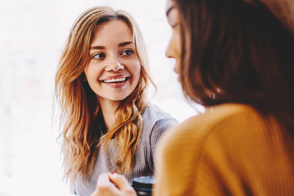 Улыбающиеся девушки-подростки, наслаждающиеся дружеской встречей, обсуждают позитивную литературу, бестселлер в помещении, счастливые успешные девушки-хипстеры, проводящие время вместе для учебы в университетском городке
