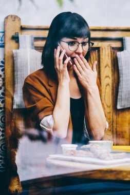 Şok haber yolu ile dizüstü bilgisayar aygıt yolu ile smartphone telefon, sürpriz kadın arkadaşıyla telefonda uygulama kullanarak söz meslektaşı ile bilgi paylaşımı web sitesinde okumak merak hippi kız