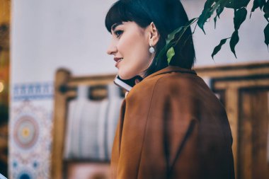 Gülümseyen esmer kadın kafeterya, Genç olumlu hippi kız arkadaş yolu ile modern smartphone aygıt ile 4 g ile konuşurken, eğitim sırasında telefon görüşmesi için hücresel uygulamasını kullanarak Internet