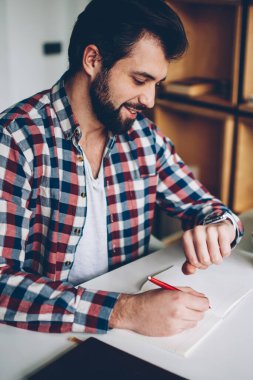 Kol saati kapalı, hipster çalışırken görünen beyaz sakallı genç adam adam öğrenme ve zaman içinde vasıl okul sırası not etmek yaratıcı düşünce için makale yazarken giyilebilir saati kontrol 20s