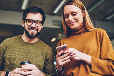 Kahve holding ve kadın blogger cep telefonu 4 g bağlantısı ile uygulama kullanarak yeni yayın oluşturma sırasında arkadaşıyla vakit Eyewear mutlu yakışıklı hipster adam portresi