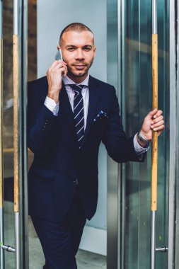 Formal giyim başarılı girişimci portresi smartphone telefon görüşmesinde office şirket ve açılış cam kapıdan gidin. İşadamı cep telefonu tatilinde gidiş: çağrı