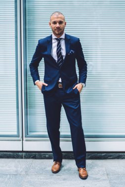 Başarılı genç portresi tam uzunlukta pahalı takım elbise ayakta duvara kopyalama alanı alanı ile sokakta gurur CEO'su dostum. Cebinde elele ve kameraya bakarak müreffeh işadamı