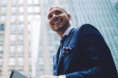 Formal giyim uzağa 4 g internet yüksek gökdelenler ile modern şehir merkezinde yürüyüş kullanarak dijital tablet uygulaması yüklenirken seyir aşağıda mutlu başarılı girişimci görünümü giymiş