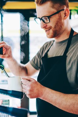 Optik gözlük beyaz erkek barista deneyimli kendi kafeteryasında emrindeki ayakta, bar ve hazırlama kahve içecek. Modern makine çalışma işlemi sırasında kullanarak kafe mutlu çalışanı