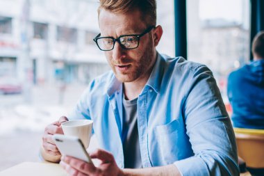 Genç işadamı posta ile bildirim smartphone aygıtında kafeteryada lezzetli kahve içme sırasında kontrol. Online sosyal ağlar Cafe mola sırasında içecek keyfini sohbet hipster adam