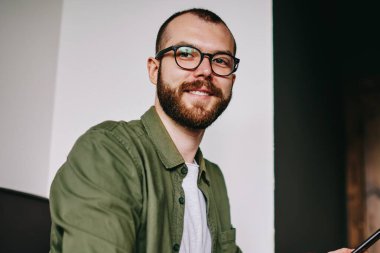 Yakışıklı hipster adam laptop, cep telefonu için sohbet ve paylaşım smartphone multimedya dosyaları ile netbook için bluetooth bağlantısı kullanarak tutan serbest meslek işten dikkati portresi