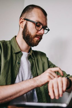 Yakışıklı delikanlı laptop en sevdiğim kafede, Erkek masada oturan ve bekleyen son gadget'ı organize ederken bilgisayarla çalışma fotoğraf yolu ile sohbet ederken onun smartwatch zamanında kontrol