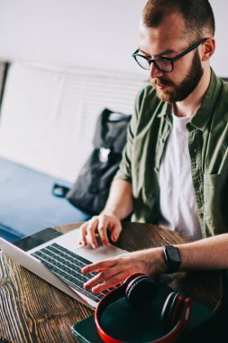 Genç tasarımcı yeni modern laptop kullanırken rahat öğrenci kafede oturan, hipster adam gözlük paylaşımında sosyal ağ ileti arkadaşlar profilinde, içerik çevrimiçi öğretici izlerken