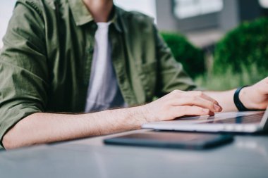 Yeni dizüstü bilgisayar, bilgi aramak ve serbest netbook açık havada üzerinde klavye üzerinde çalışan erkek programcı yazarak Sokak kafede oturan genç beyaz hipster biri kırpılmış görüntü